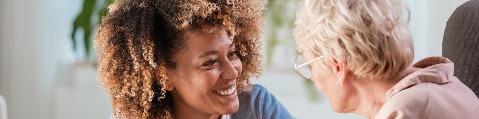 A senior woman looking at her female caregiver smiling at her