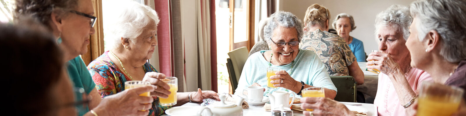 A group of seniors enjoying breakfast at a table in a dining area in a senior living facility