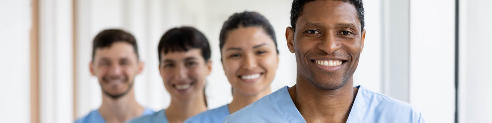 Four senior living facility employees standing in a staggered line smiling