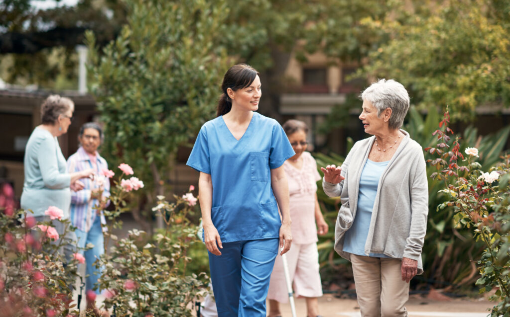 A senior woman walking outdoors with a senior living employee